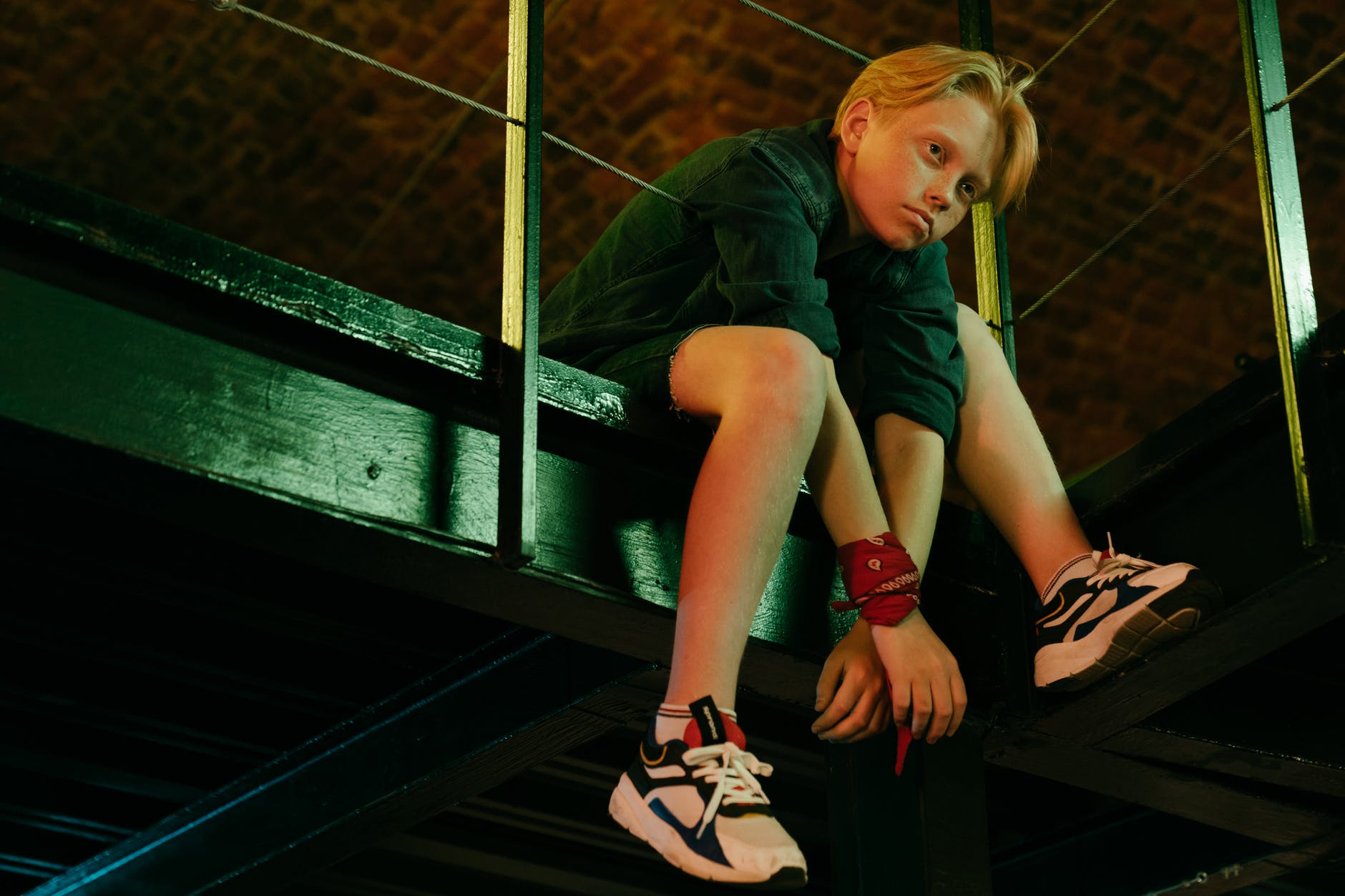 woman in green shirt sitting on black metal railings