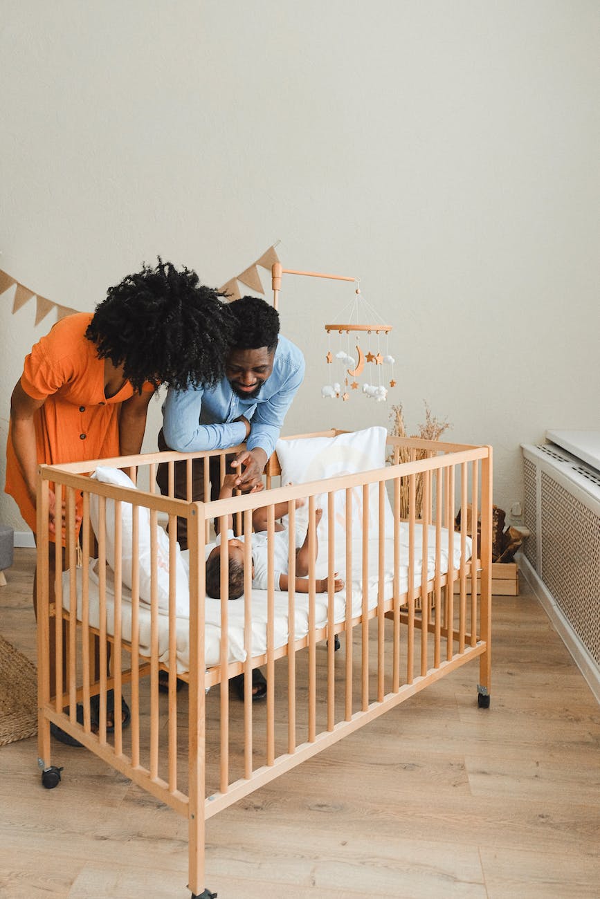 couple standing beside a baby in a cot
